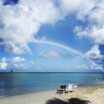chairs on a beach with a rainbow
