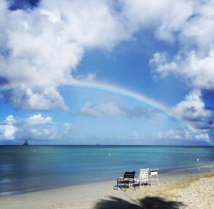 chairs on a beach with a rainbow