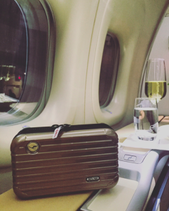 a suitcase and a glass of wine on a table next to a window