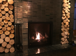 a fireplace with fire in the middle of a wall of logs