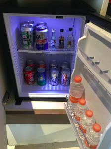 a mini fridge with bottles of soda and cans