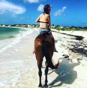 a woman riding a horse on a beach