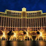 a large building with lights and water fountains with Bellagio in the background