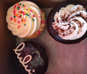 a box of cupcakes with frosting and sprinkles