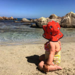 a baby sitting on a beach