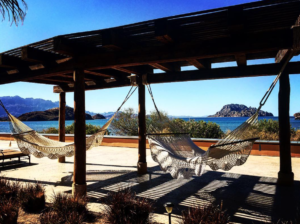 hammocks on a patio with a view of the water and mountains in the background
