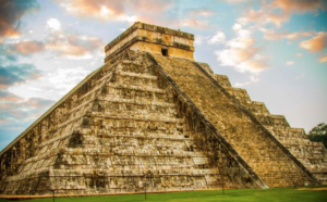 a large stone pyramid with a square top with Chichen Itza in the background