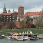 a group of boats on water next to Wawel Castle