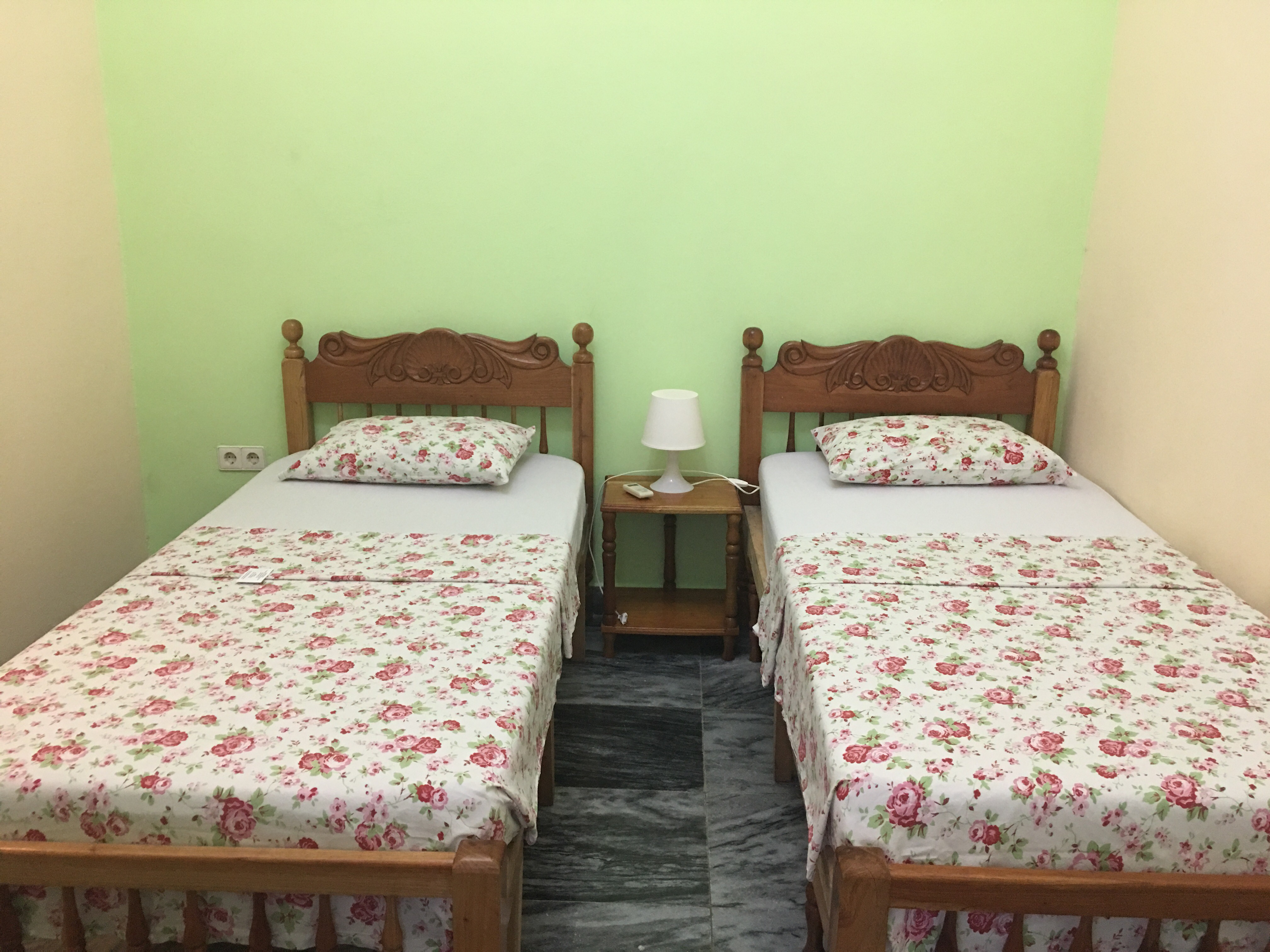 two beds with floral bedspreads and a lamp