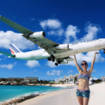 a woman standing on a beach with a plane flying above her