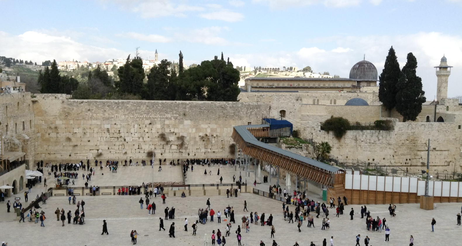 a group of people in a courtyard with Western Wall in the background