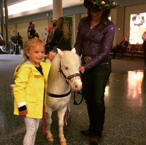 a woman and a little girl petting a white pony