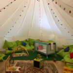 a white tent with green pillows and toys