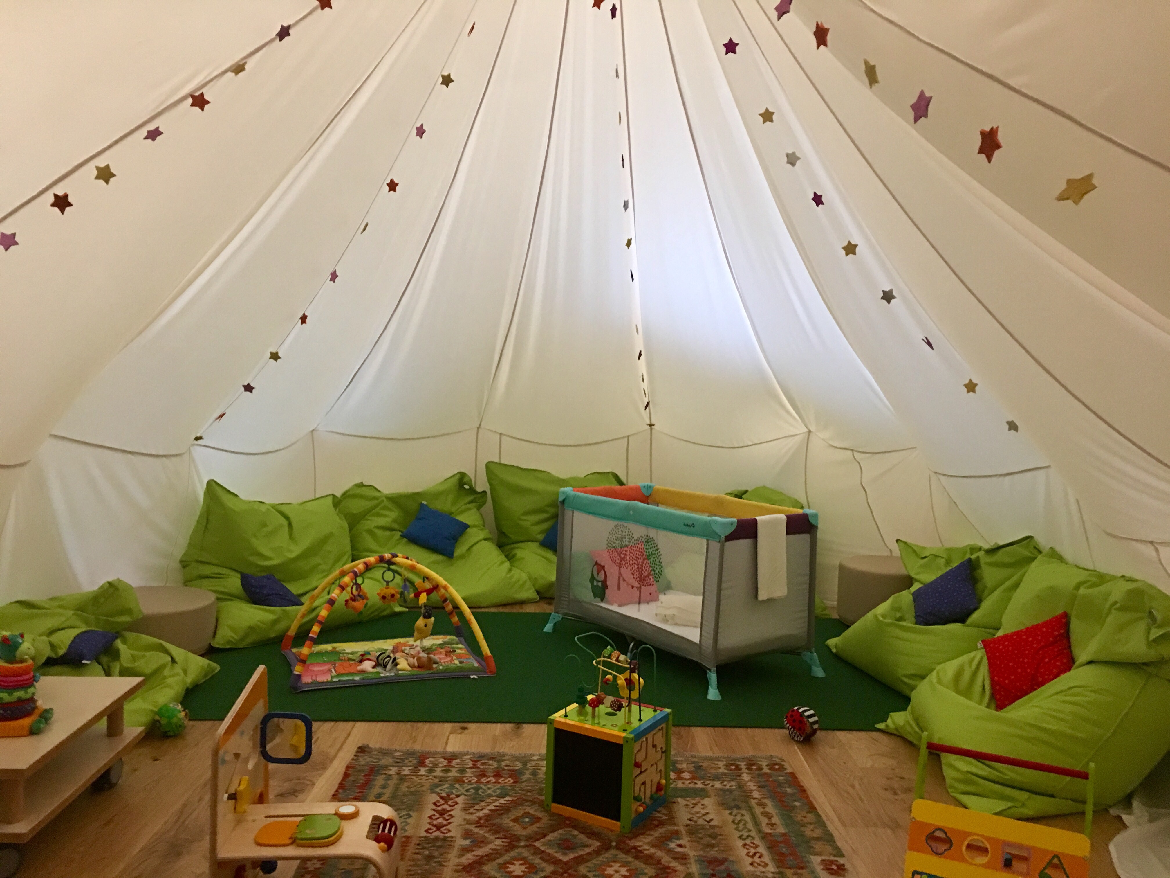 a white tent with green pillows and toys