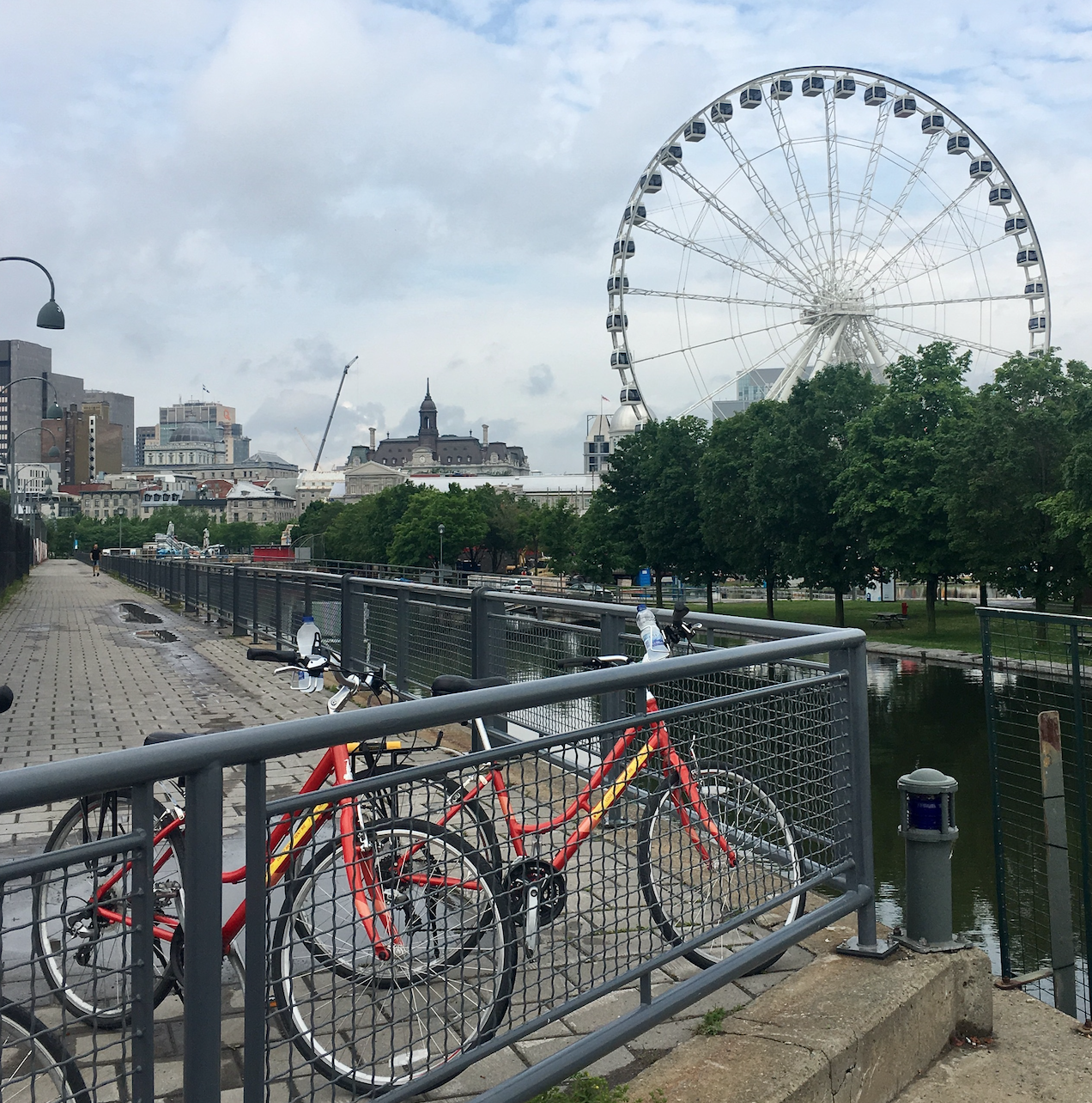 a bicycle parked on a bridge next to a body of water and a ferris wheel
