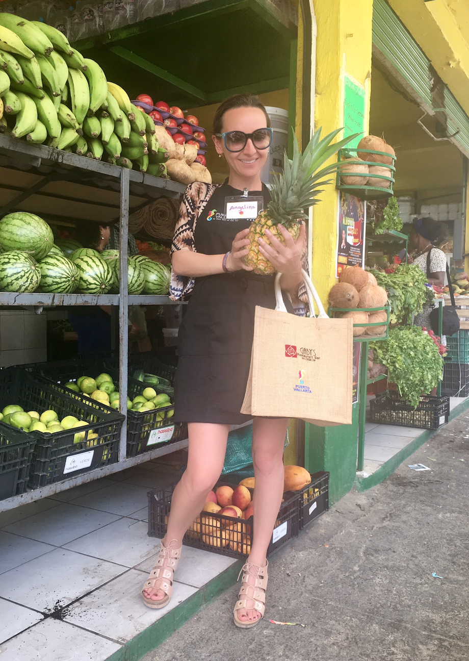 a woman holding a pineapple and a bag in front of a store
