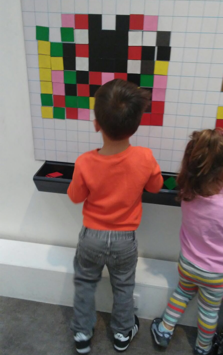 a boy and girl playing with colorful squares on a white board