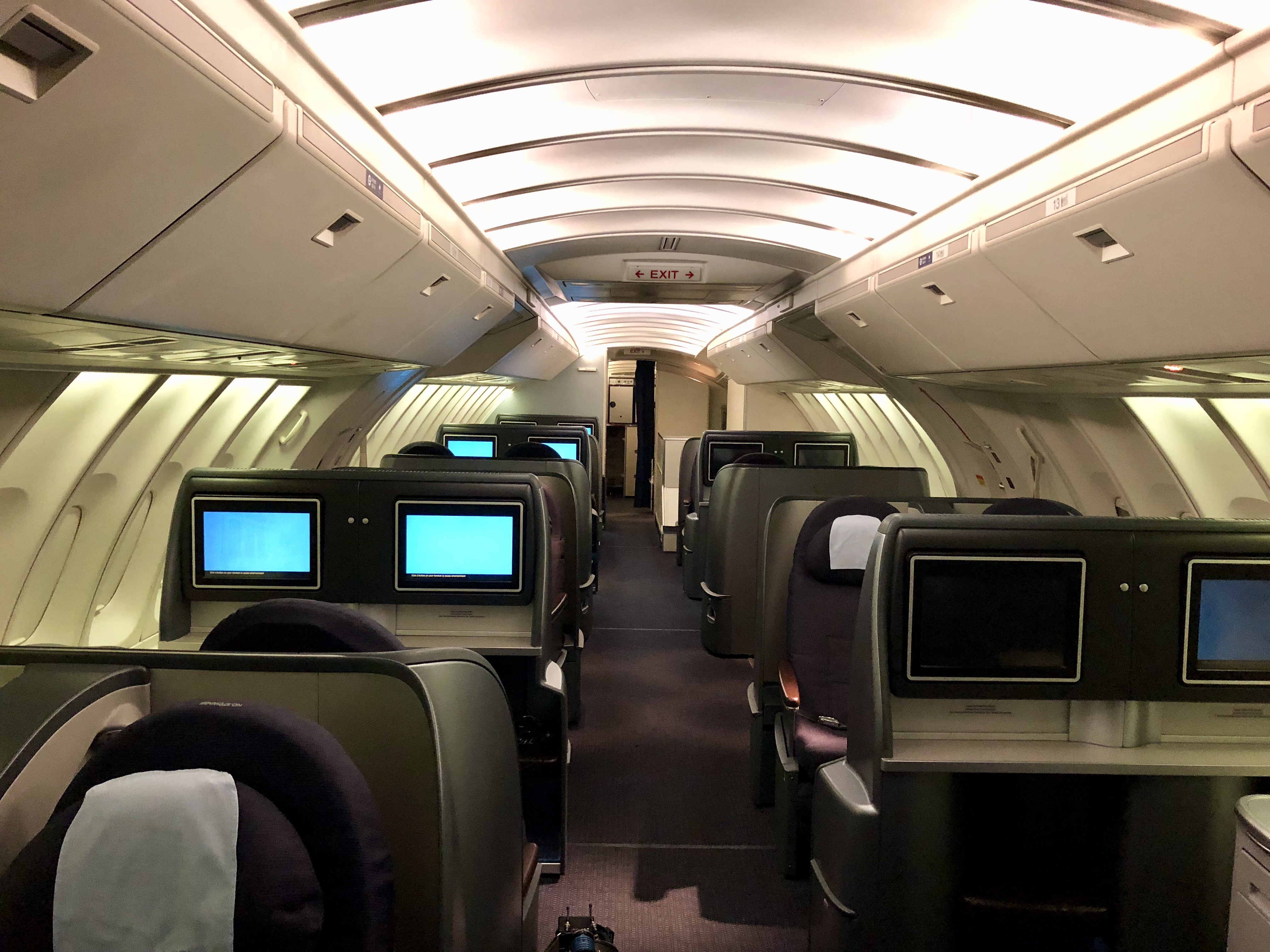 the inside of an airplane with rows of seats and monitors