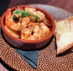 a bowl of shrimp with a slice of bread on a plate