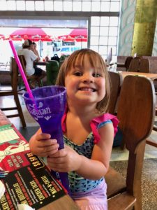 a girl holding a purple cup with a straw