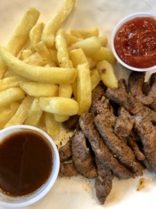 a plate of steak and fries with sauces