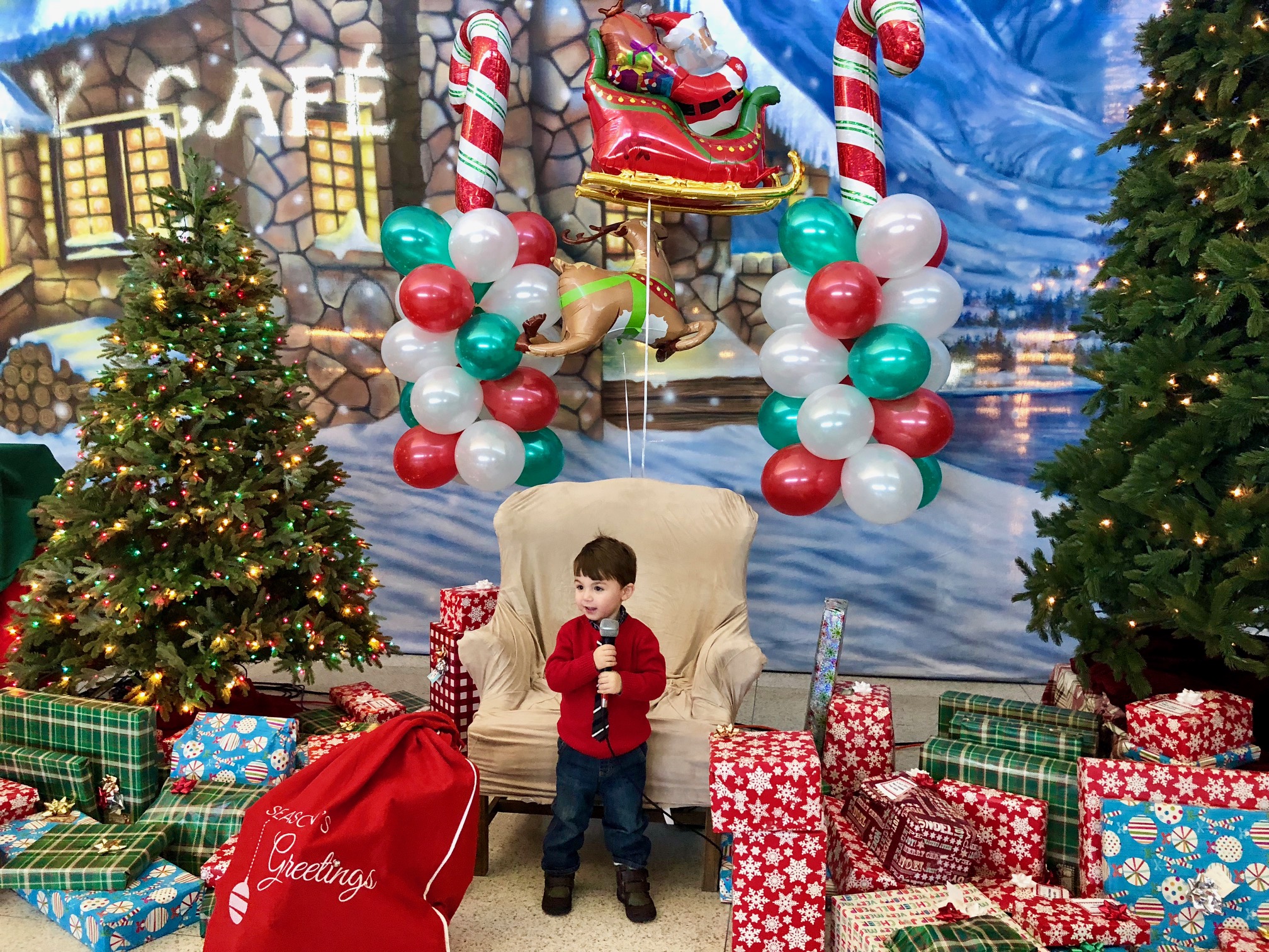 a child standing in front of a chair with balloons and presents