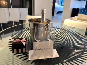 a champagne bottle in a bucket and two wine glasses on a glass table