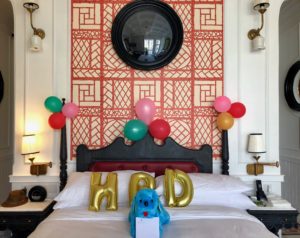 balloons on a bed with balloons and a blue stuffed animal