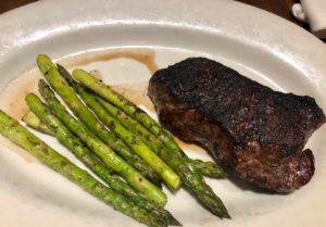 a plate of food with a piece of steak and asparagus