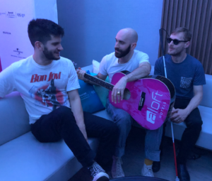 a group of men sitting on a couch playing guitar