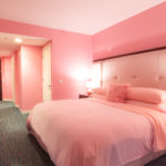 a pink bedroom with a bed and a lamp