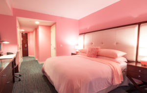 a pink bedroom with a bed and a lamp