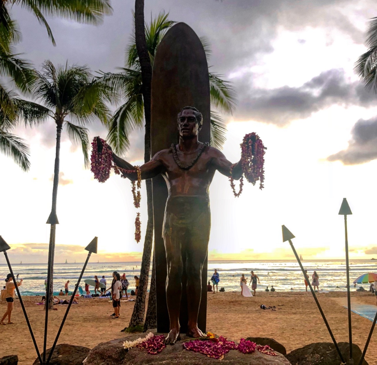 a statue of a man holding a surfboard and leis
