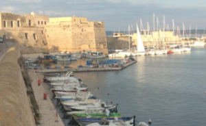 boats in a harbor with a stone building and boats