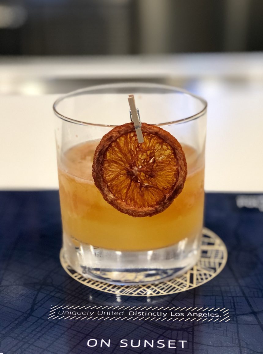 a glass with a drink and a slice of orange on it