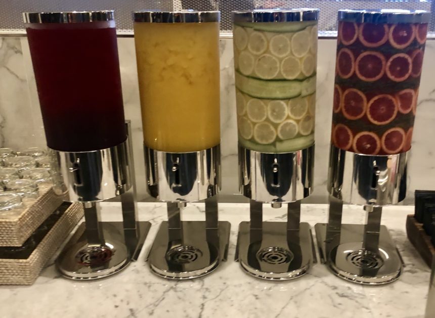 a group of juice dispensers with different colored liquid